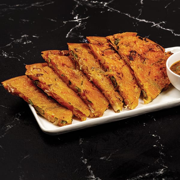 Antoya Korean BBQ's kimchi pancake, sliced and served with a dipping sauce on a white plate.