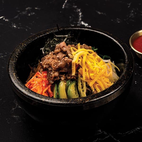 Antoya Korean BBQ's bibimbap with beef, egg, carrots, and zucchini in a black stone bowl.